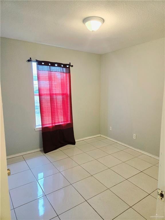 unfurnished room featuring a textured ceiling and light tile patterned floors