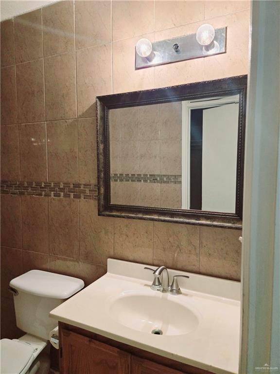 bathroom featuring vanity, tasteful backsplash, tile walls, and toilet