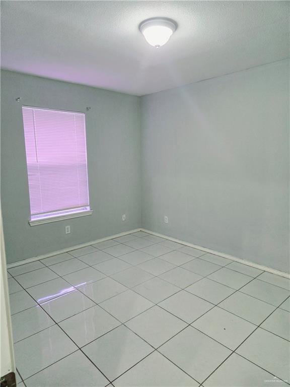 spare room featuring light tile patterned floors and a textured ceiling