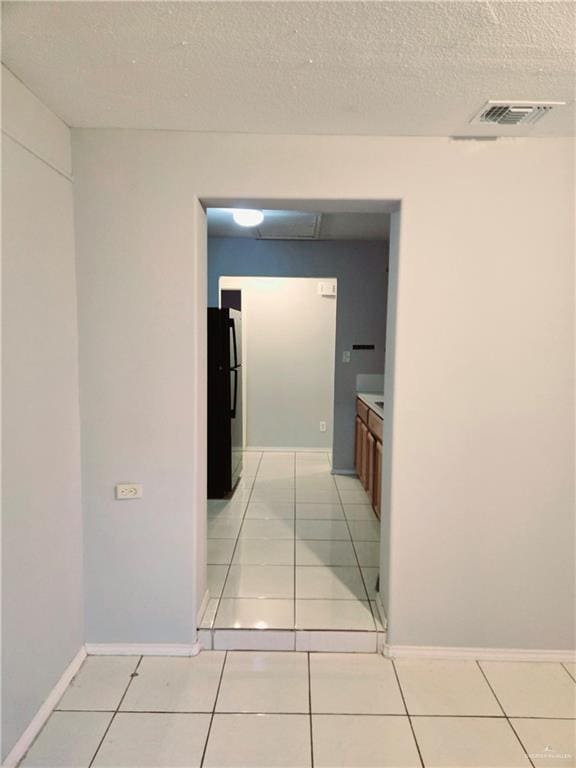 corridor with light tile patterned flooring and a textured ceiling