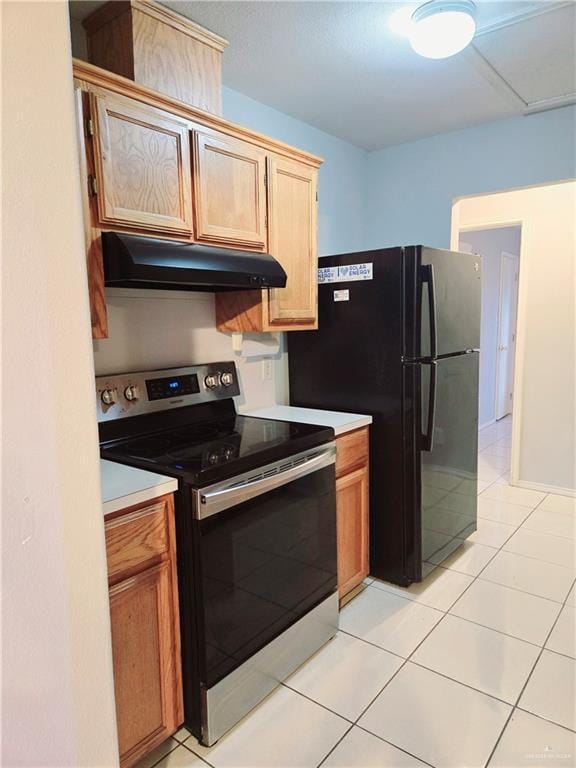 kitchen with stainless steel electric range oven, black fridge, and light tile patterned flooring