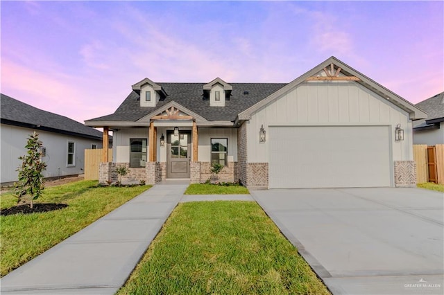 view of front of home featuring a front lawn, board and batten siding, driveway, brick siding, and a garage