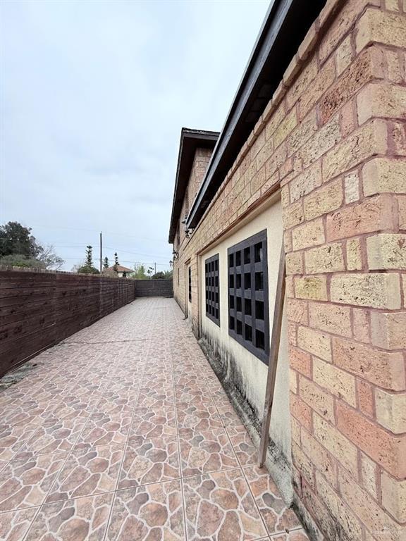 view of property exterior with brick siding and fence