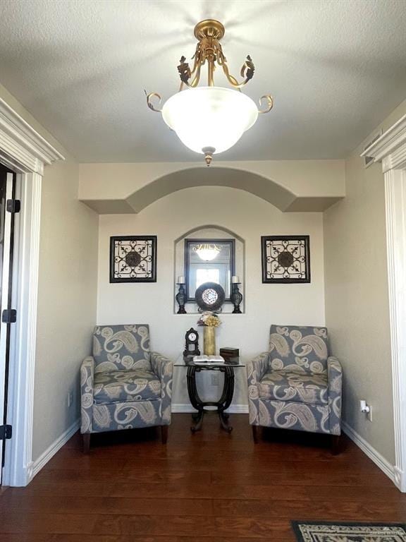 sitting room with a textured ceiling, baseboards, and wood finished floors