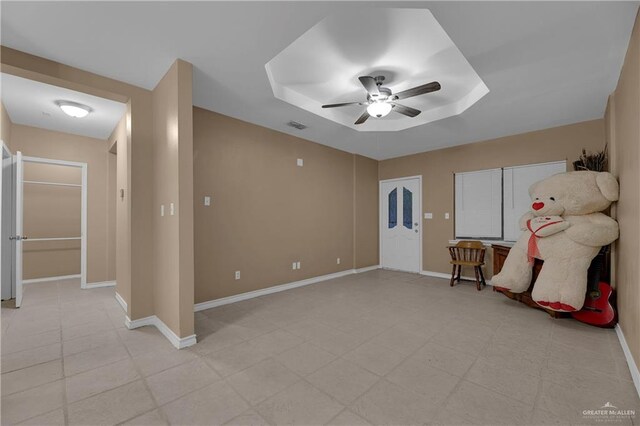 empty room featuring ceiling fan and a raised ceiling