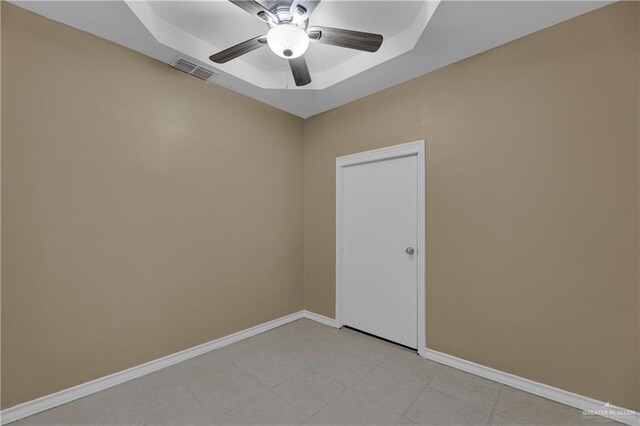 empty room with a raised ceiling and ceiling fan