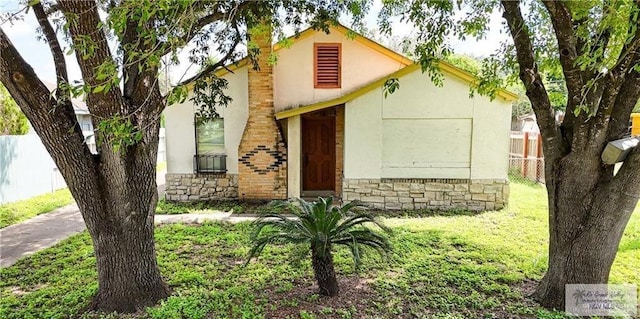 1005 S Nebraska Ave, Weslaco, TX 78596 - view of front of home featuring fence, stone siding, stucco siding, and a front yard