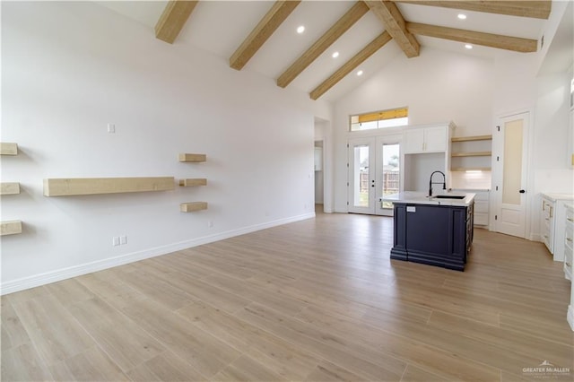 kitchen with a sink, high vaulted ceiling, open floor plan, and light countertops