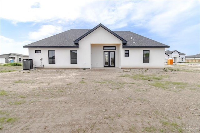 back of property featuring central AC unit, french doors, roof with shingles, and stucco siding