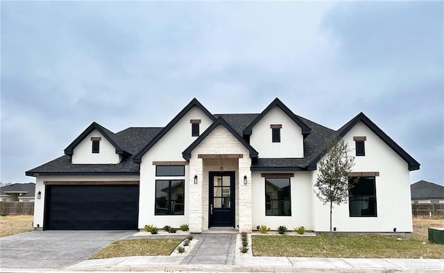 view of front of home featuring stucco siding, a garage, driveway, and fence