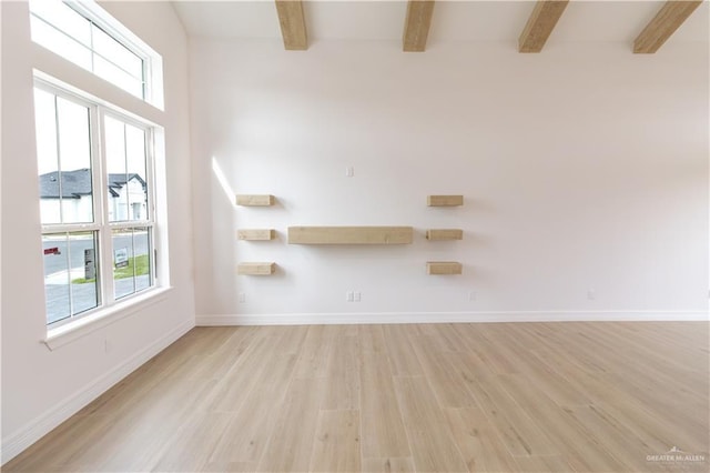 spare room with light wood-type flooring, beamed ceiling, and baseboards