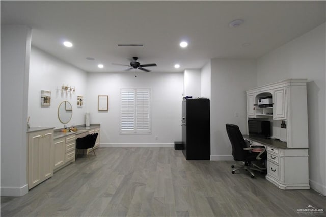 office with light wood-type flooring, ceiling fan, and built in desk