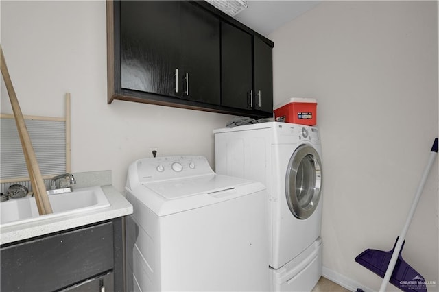 clothes washing area featuring cabinets, sink, and washer and clothes dryer