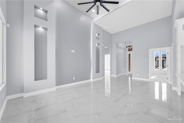 unfurnished living room featuring ceiling fan and a towering ceiling