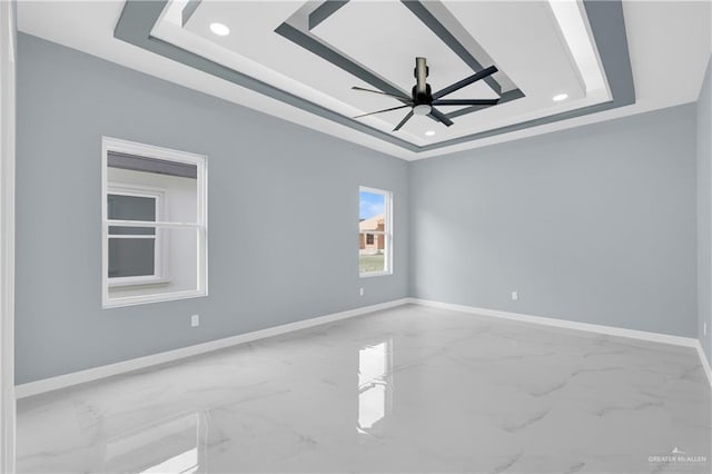 empty room with marble finish floor, baseboards, and a raised ceiling