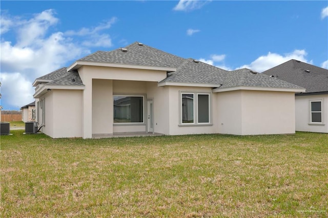 back of property with central air condition unit, a lawn, and roof with shingles