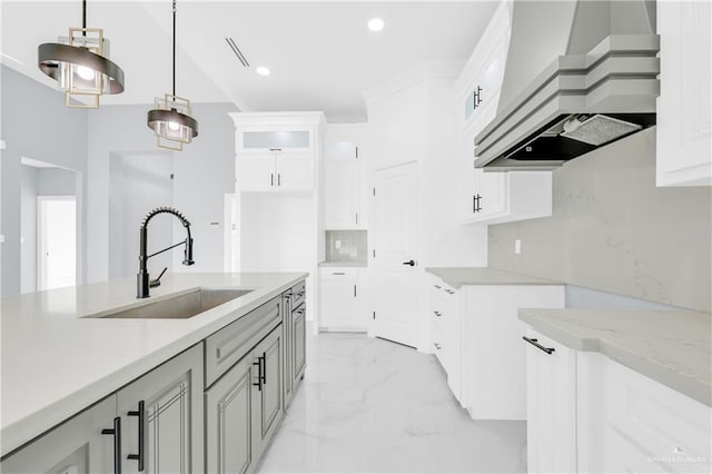 kitchen featuring sink, premium range hood, decorative backsplash, white cabinets, and decorative light fixtures