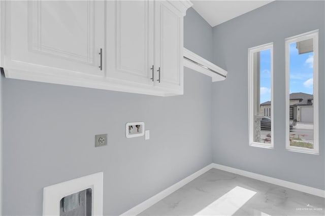 washroom with hookup for an electric dryer, washer hookup, baseboards, marble finish floor, and cabinet space