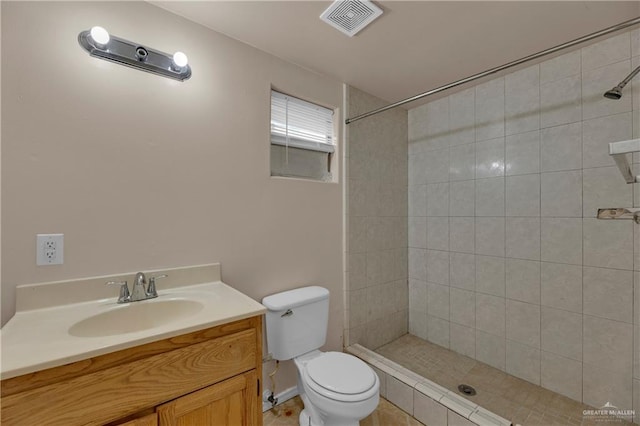 bathroom with tile patterned flooring, vanity, toilet, and a tile shower