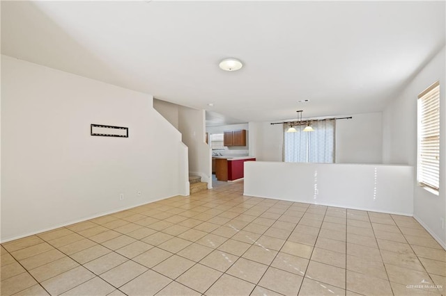 tiled empty room with an inviting chandelier