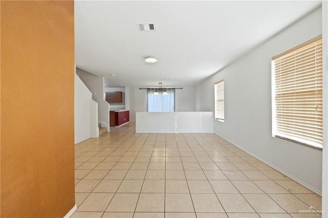 tiled empty room featuring a chandelier