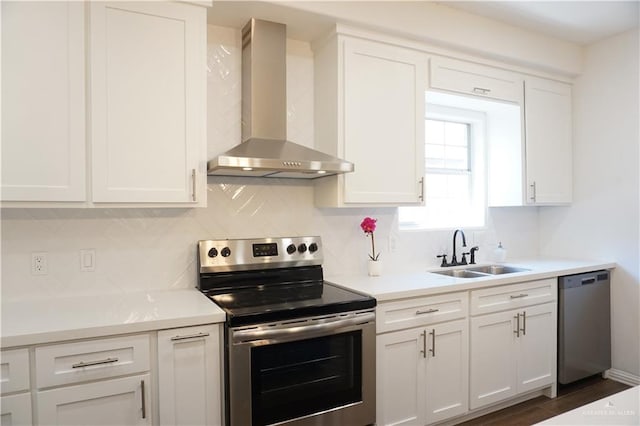 kitchen with appliances with stainless steel finishes, dark hardwood / wood-style flooring, sink, wall chimney range hood, and white cabinetry