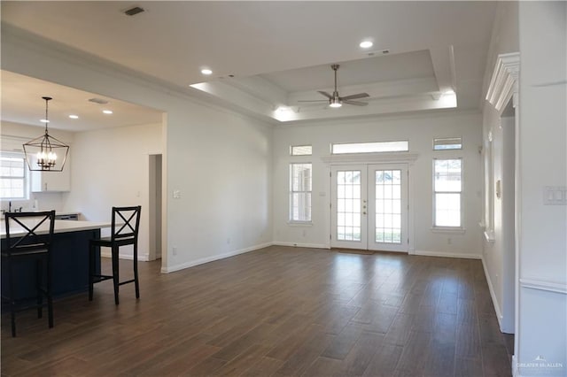 living room featuring french doors, ceiling fan with notable chandelier, a tray ceiling, and dark wood-type flooring