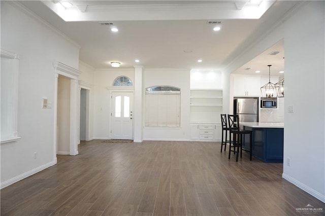 entrance foyer with dark hardwood / wood-style flooring, a chandelier, and ornamental molding