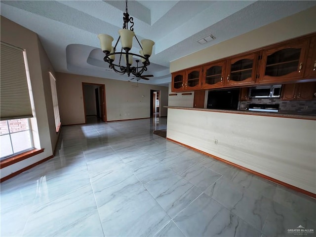 kitchen with pendant lighting, an inviting chandelier, a raised ceiling, fridge, and range