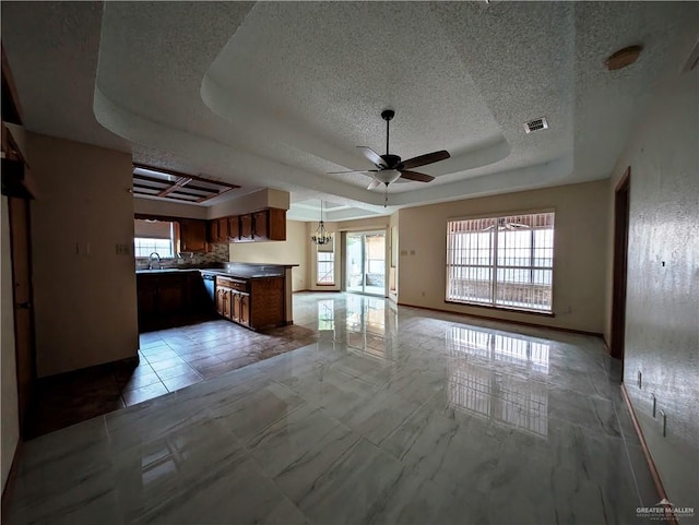 kitchen featuring kitchen peninsula, a textured ceiling, a tray ceiling, ceiling fan, and sink