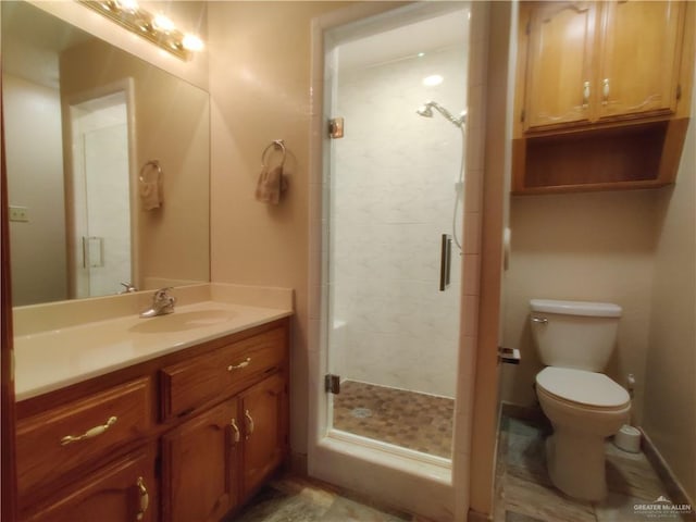 bathroom with vanity, toilet, and a shower with door