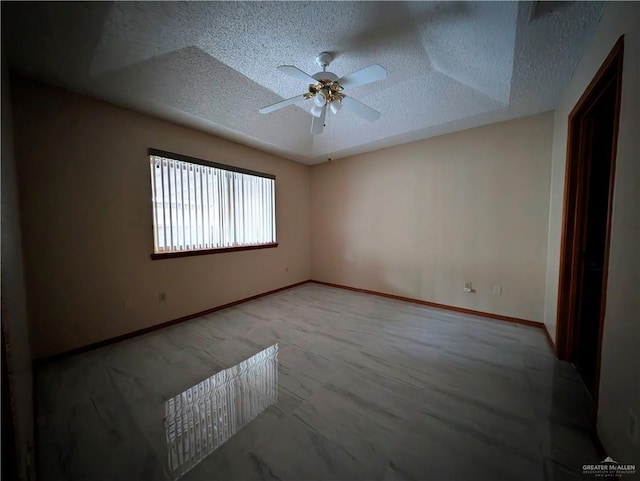 empty room featuring a textured ceiling, a raised ceiling, and ceiling fan