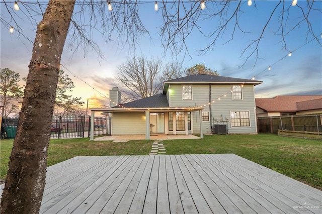 back of property at dusk featuring a deck, central air condition unit, a lawn, and a fenced backyard