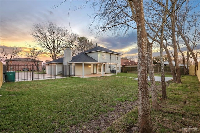 rear view of property with a patio area, a lawn, a chimney, and a fenced backyard