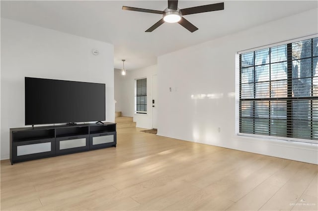 living area featuring stairway, a ceiling fan, and light wood-type flooring