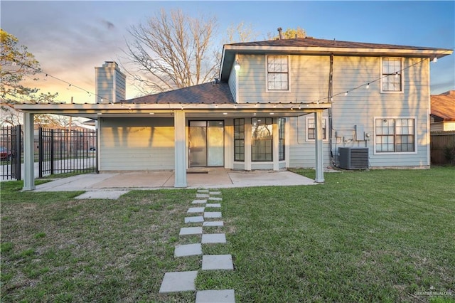 rear view of house featuring a patio, fence, a yard, central AC, and a chimney