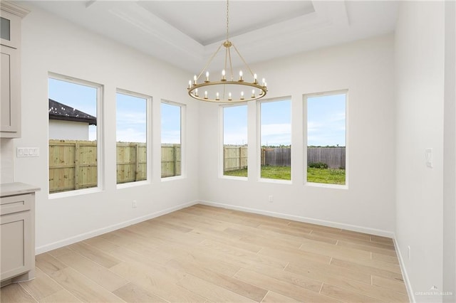 1003 Bette St, Pharr, TX 78577 - unfurnished dining area featuring a raised ceiling, light wood-style flooring, a wealth of natural light, and a notable chandelier