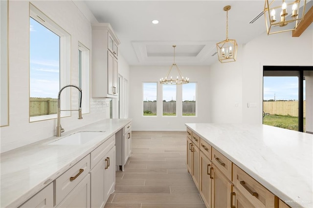 1003 Bette St, Pharr, TX 78577 - kitchen featuring hanging light fixtures, a sink, light wood finished floors, a raised ceiling, and a notable chandelier
