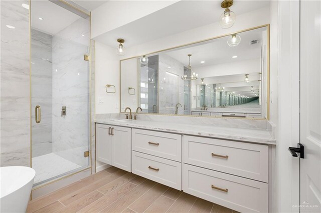 1003 Bette St, Pharr, TX 78577 - full bathroom featuring visible vents, wood finished floors, a marble finish shower, and vanity