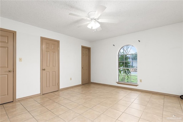 empty room featuring ceiling fan, a textured ceiling, and light tile patterned floors