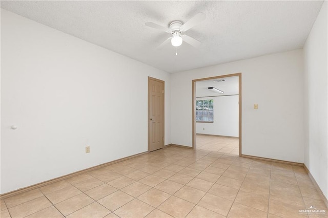 spare room with a textured ceiling, ceiling fan, and light tile patterned flooring