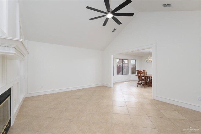 unfurnished living room with ceiling fan with notable chandelier, high vaulted ceiling, a glass covered fireplace, and visible vents