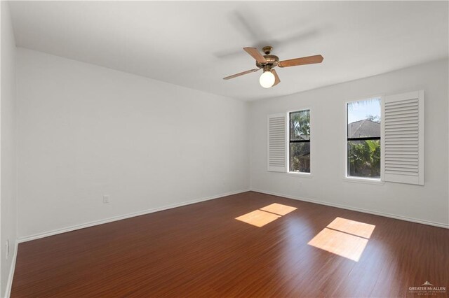 spare room with ceiling fan, dark wood-type flooring, and baseboards