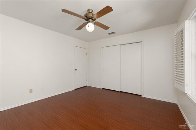 unfurnished bedroom featuring dark wood-style floors, baseboards, visible vents, and a ceiling fan