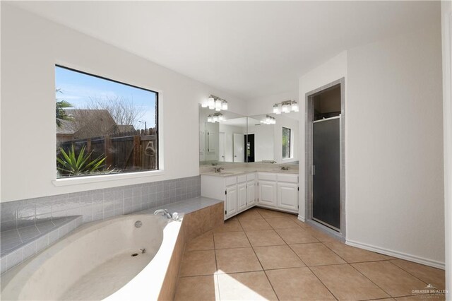 bathroom with double vanity, a stall shower, a sink, tile patterned flooring, and a bath