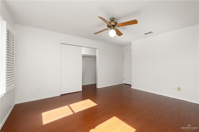 unfurnished bedroom with a closet, wood finished floors, visible vents, and baseboards