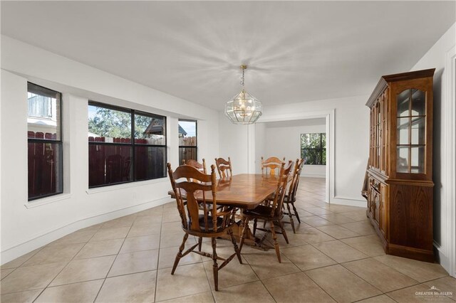 dining area featuring light tile patterned floors, baseboards, and a chandelier