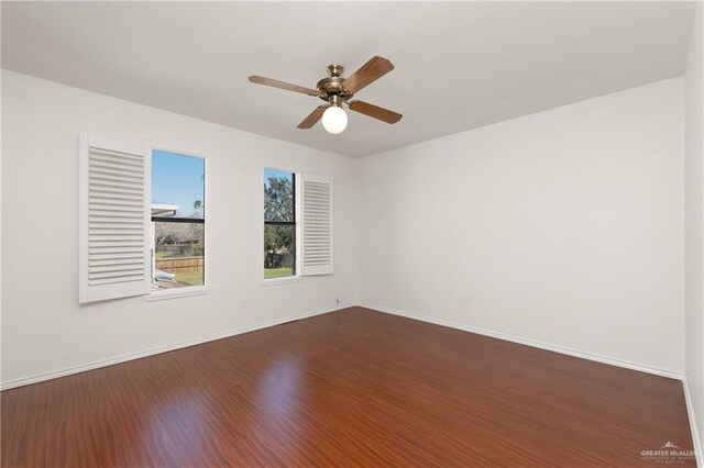 spare room with ceiling fan, dark wood-style flooring, and baseboards