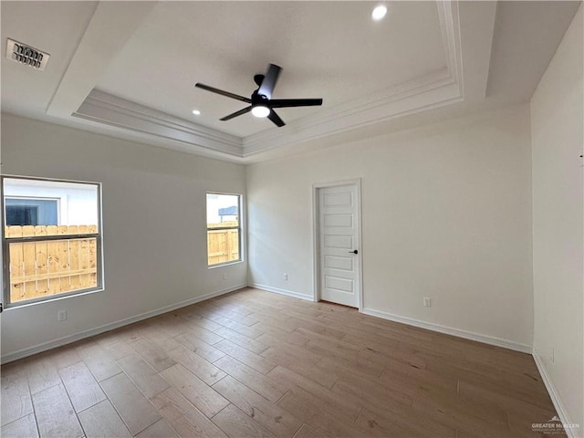 empty room with hardwood / wood-style flooring, ceiling fan, crown molding, and a tray ceiling