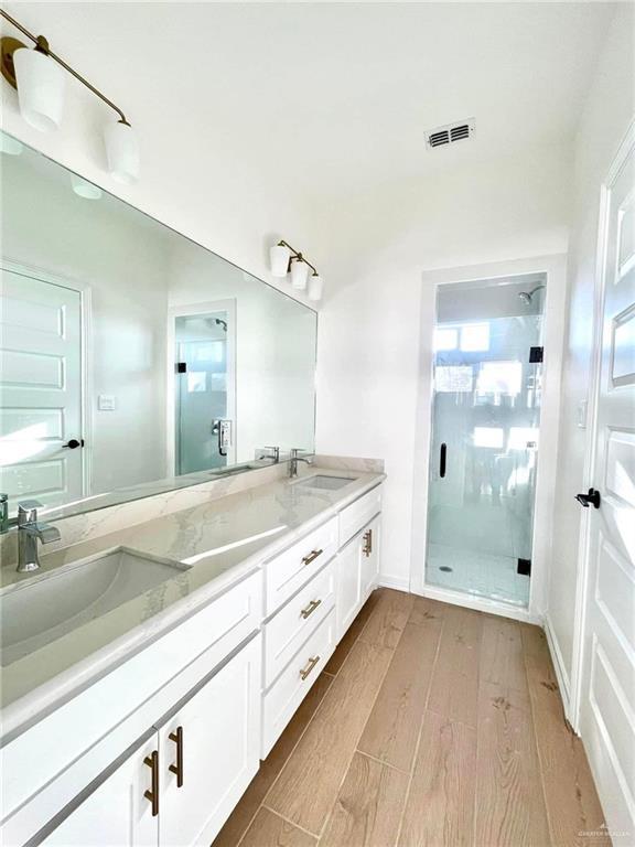 bathroom featuring hardwood / wood-style floors, vanity, a wealth of natural light, and a shower with door